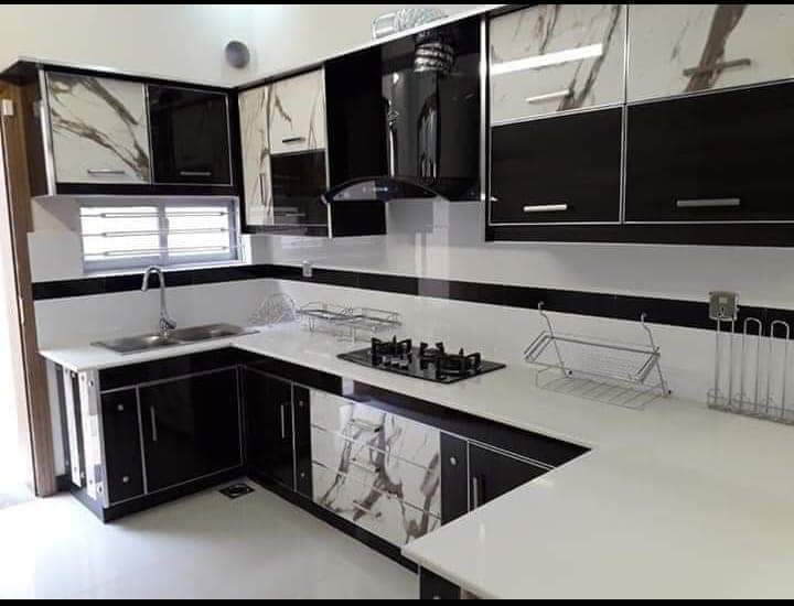 Black and white high-gloss L-shaped kitchen with marble-veined panels