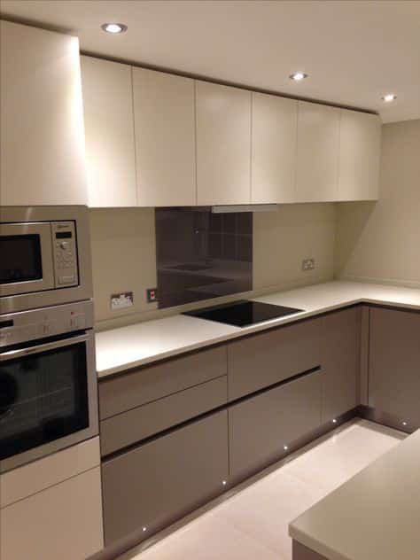 Cream and taupe handleless kitchen with black glass cooktop splashback