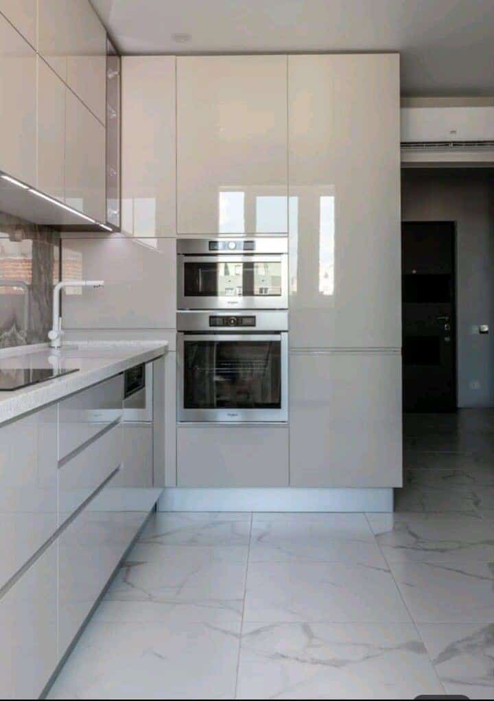 High-gloss cream kitchen with built-in double oven and LED strip lighting