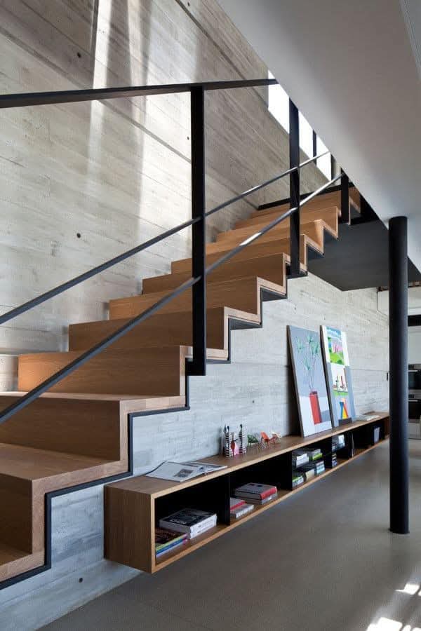 Wood staircase with black metal frame and under-stair book shelf